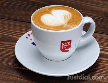 "A freshly brewed cappuccino with latte art served in a white Café Coffee Day cup, showcasing a classic coffee experience at one of the Best Cafés in India."